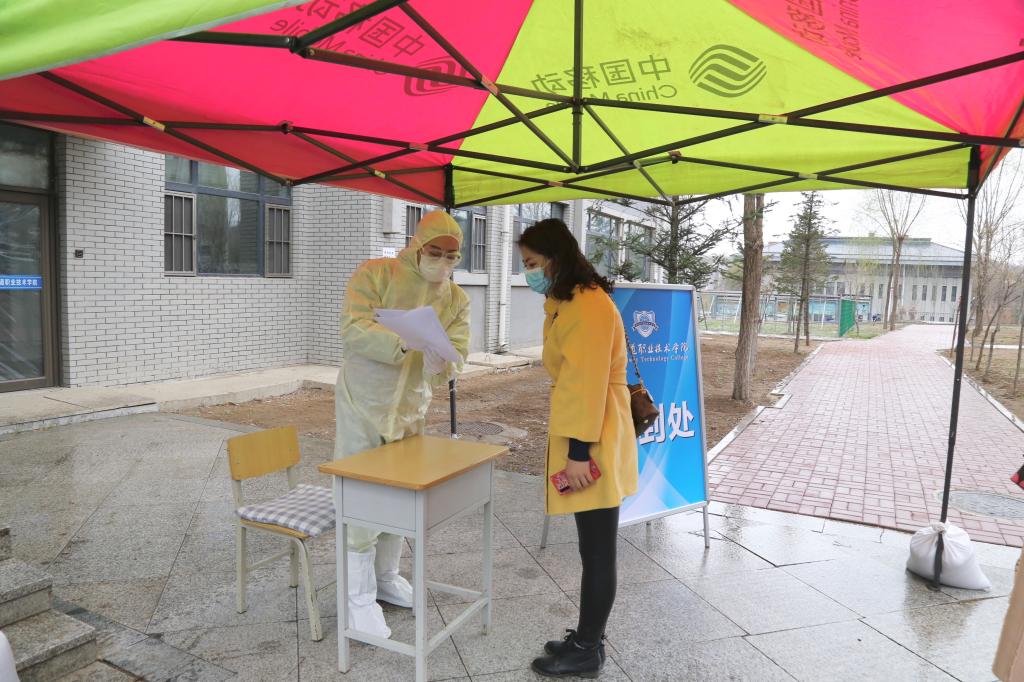 “学生”在公寓进口处签字确认《健康登记表》